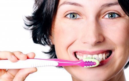Mulher sorrindo e escovando os dentes - LUZ Loja de Consultoria