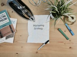 Consultoria de marketing: o que é e como fazer: papel escrito marketing strategy e outros objetos sobre a mesa